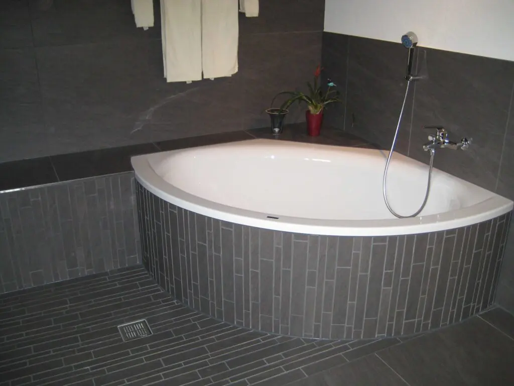 Moderne Badewanne in stilvollem Badezimmer mit eleganten, dunklen Fliesen.