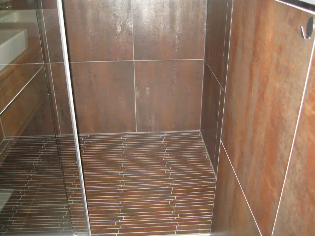Moderne Duschkabine mit braunen Wandfliesen und ebenerdiger gefliester Dusche, elegantes Badezimmerdesign.