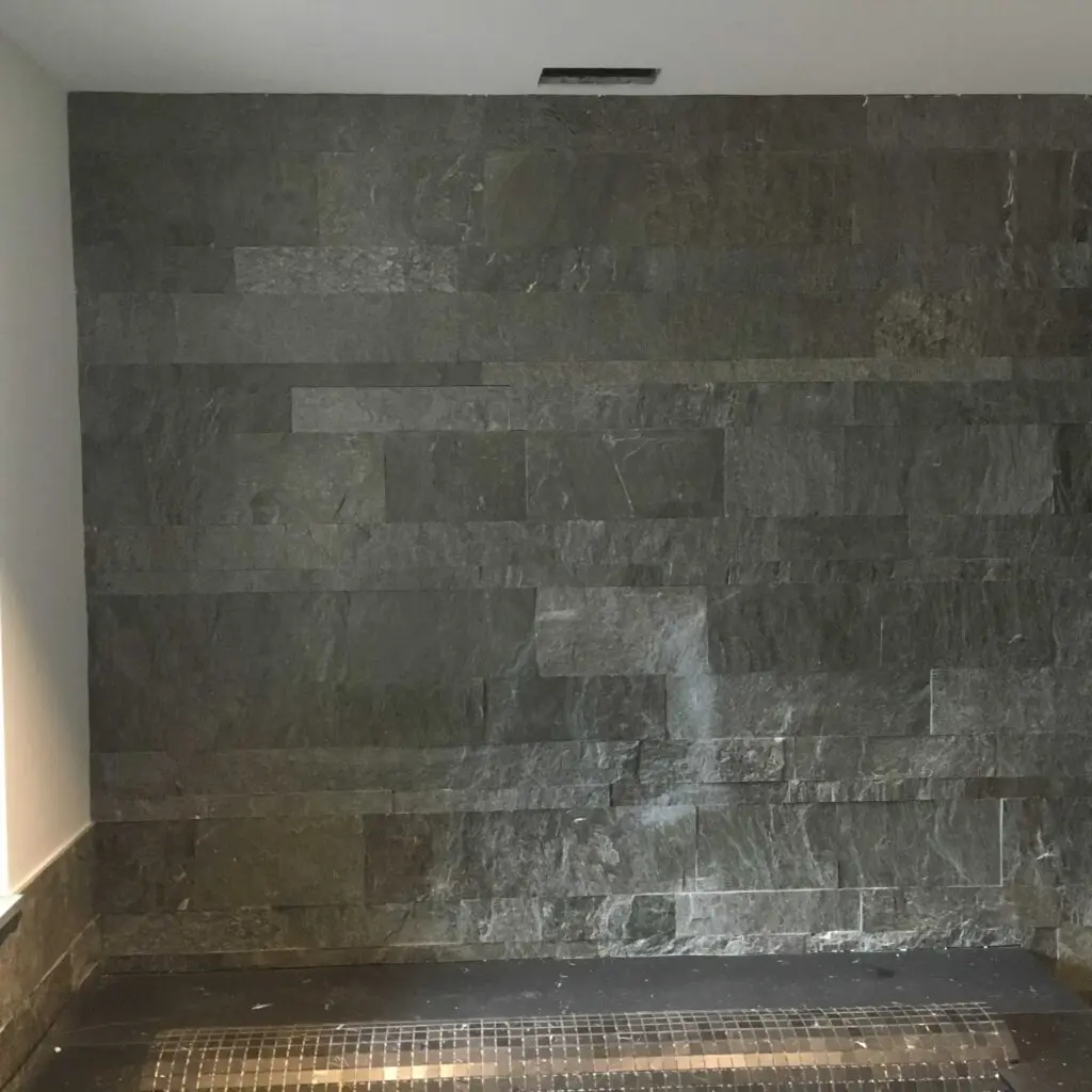 Dunkle Steinwand mit modernem Design, ideal für elegante Innenraumgestaltung und zeitgenössische Badezimmerausstattung.