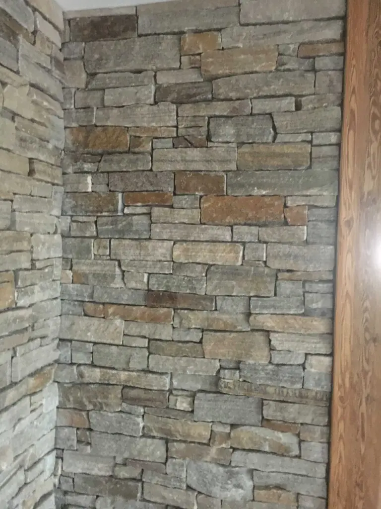 Eckige Steinwand mit natürlicher Textur und unterschiedlichen Farbtönen, ideal für rustikales oder modernes Interieur.