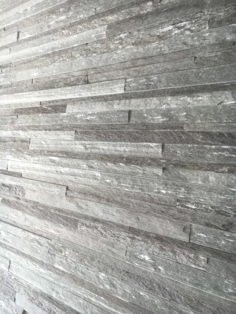 Moderne graue Steinwandverkleidung in horizontalen, strukturierten Platten, ideal für stilvolles Interieur.