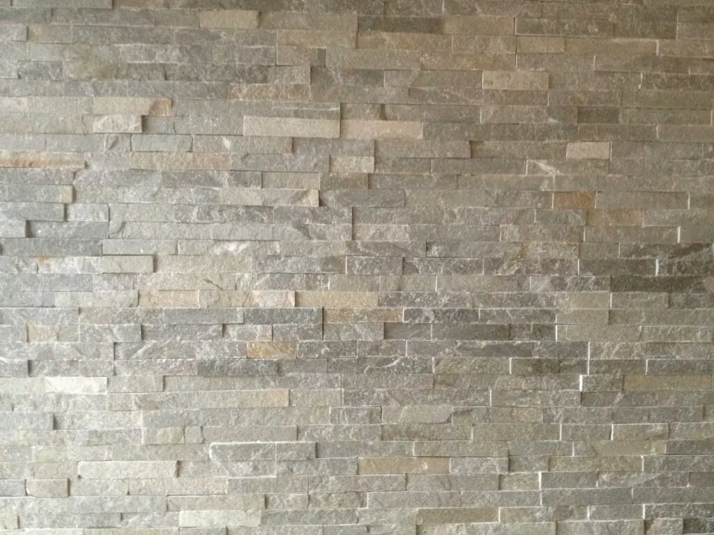 Graue Steinmauer mit rechteckigen Steinen in Schichtoptik, geeignet für modernes Innendesign und architektonische Akzente.
