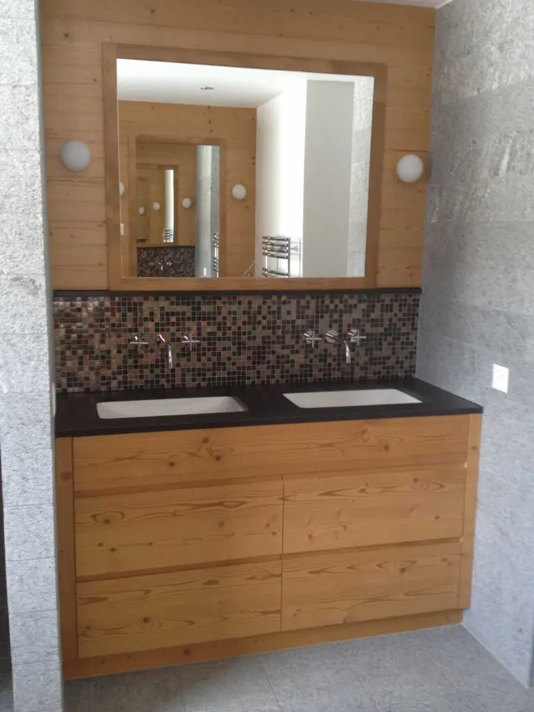 Modernes Badezimmer mit Holzunterschrank, Zwillingswaschbecken und großem Spiegel über Mosaikfliesen.