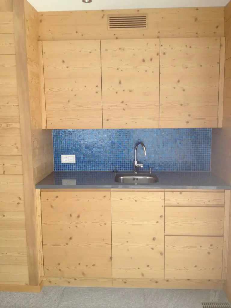 Holzküche mit blauer Fliesenrückwand, Spüle und Stauraum. Elegantes und modernes Design.