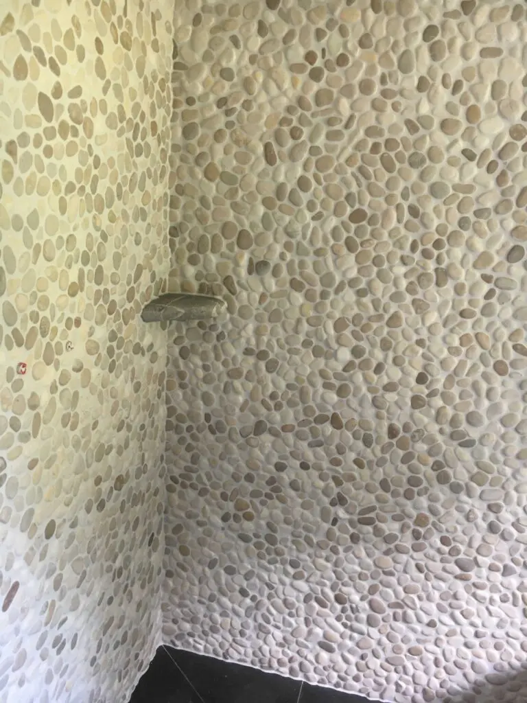 Wand mit Kieselmosaik in neutralen Tönen, stilvolle Badezimmergestaltung.