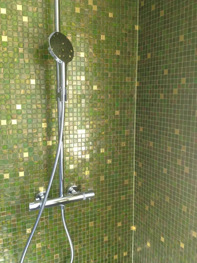 Grün geflieste Dusche mit modernem Duschkopf und eleganter Armatur für stilvolles Badezimmerdesign.