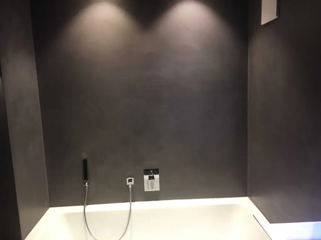 Moderne Badewanne mit dunkler Wand und integrierter Beleuchtung für ein elegantes und minimalistisches Badezimmerdesign.