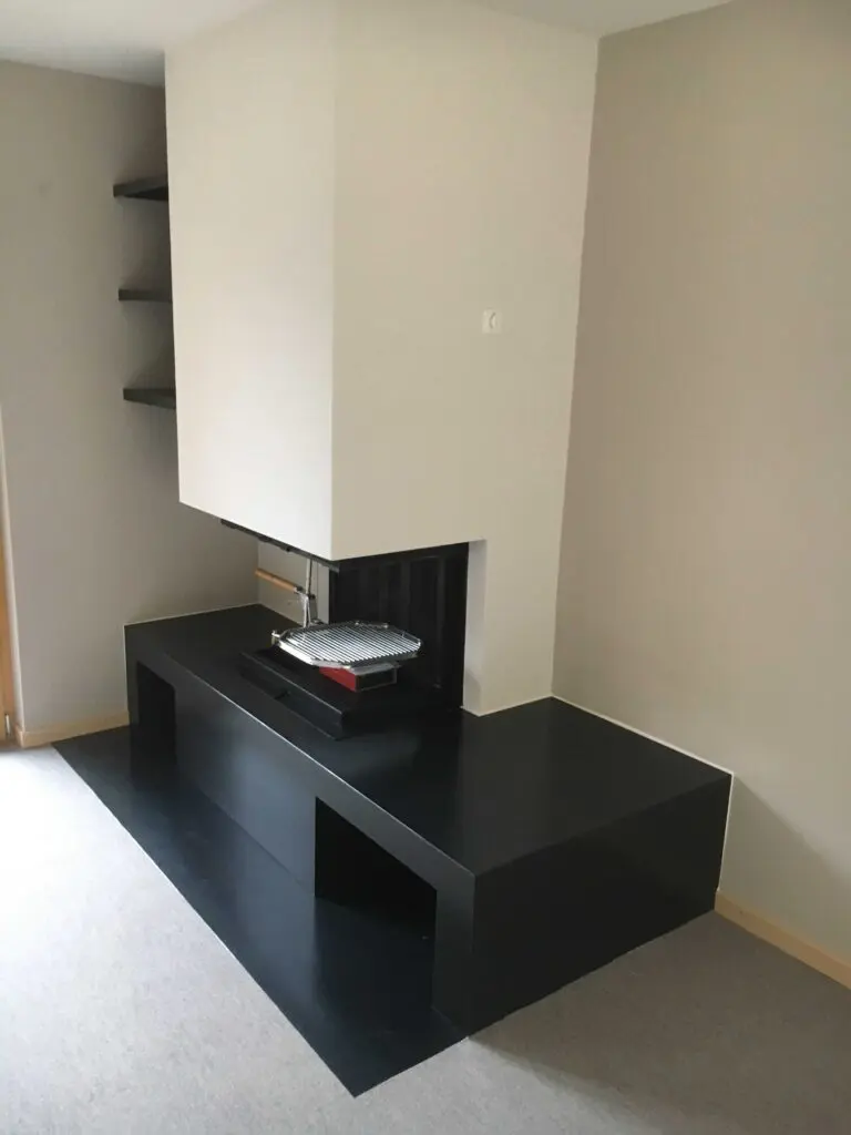 Moderner, schwarzer Kamin in minimalistischem Wohnzimmerdesign mit weißgrauen Wänden und eingebauten Regalen.