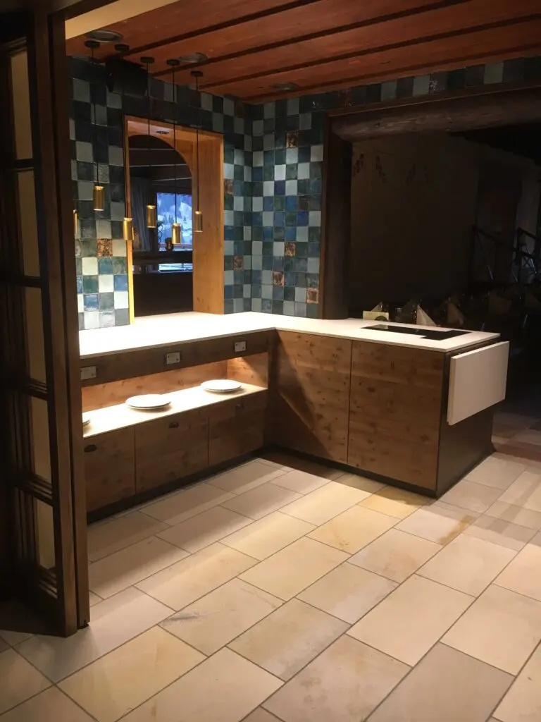 Moderne Küche mit Holzmöbeln, blauen Fliesen und Hängelampen. Perfektes Design für ein gemütliches Ambiente.