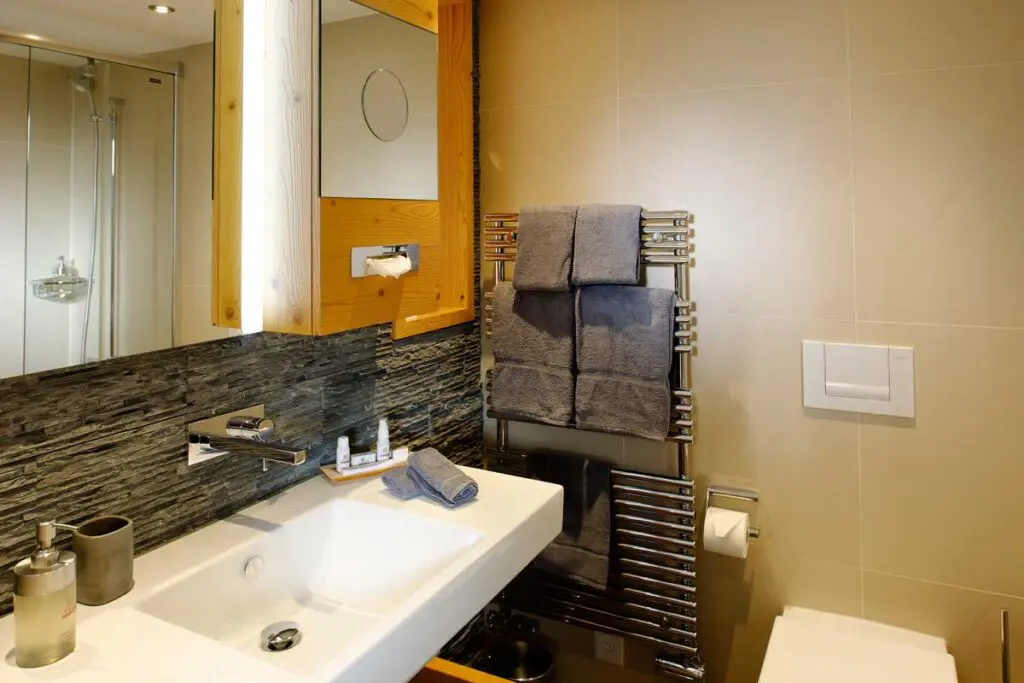 Modernes Badezimmer mit waschbecken, Handtuchheizkörper, Spiegel und eleganten Details in neutralen Tönen.