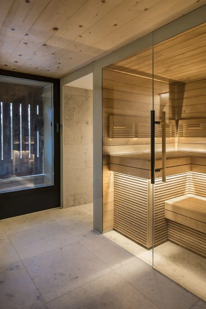 Moderne Sauna mit Glasfront, Innenansicht in warmem Holzton, beleuchtet für entspannende Erholung.