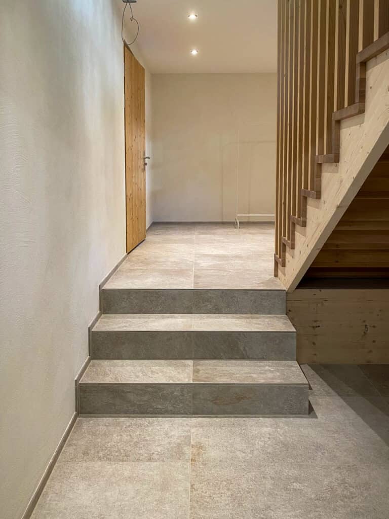 Moderner Flur mit Treppe, Holzverkleidung und Steingutfliesen, minimalistische Architektur.